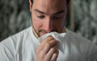 Man holding tissue to nose