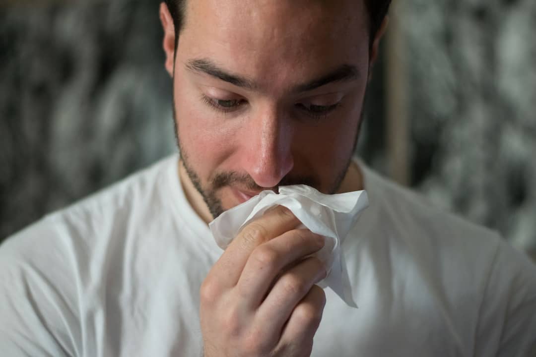 Man holding tissue to nose