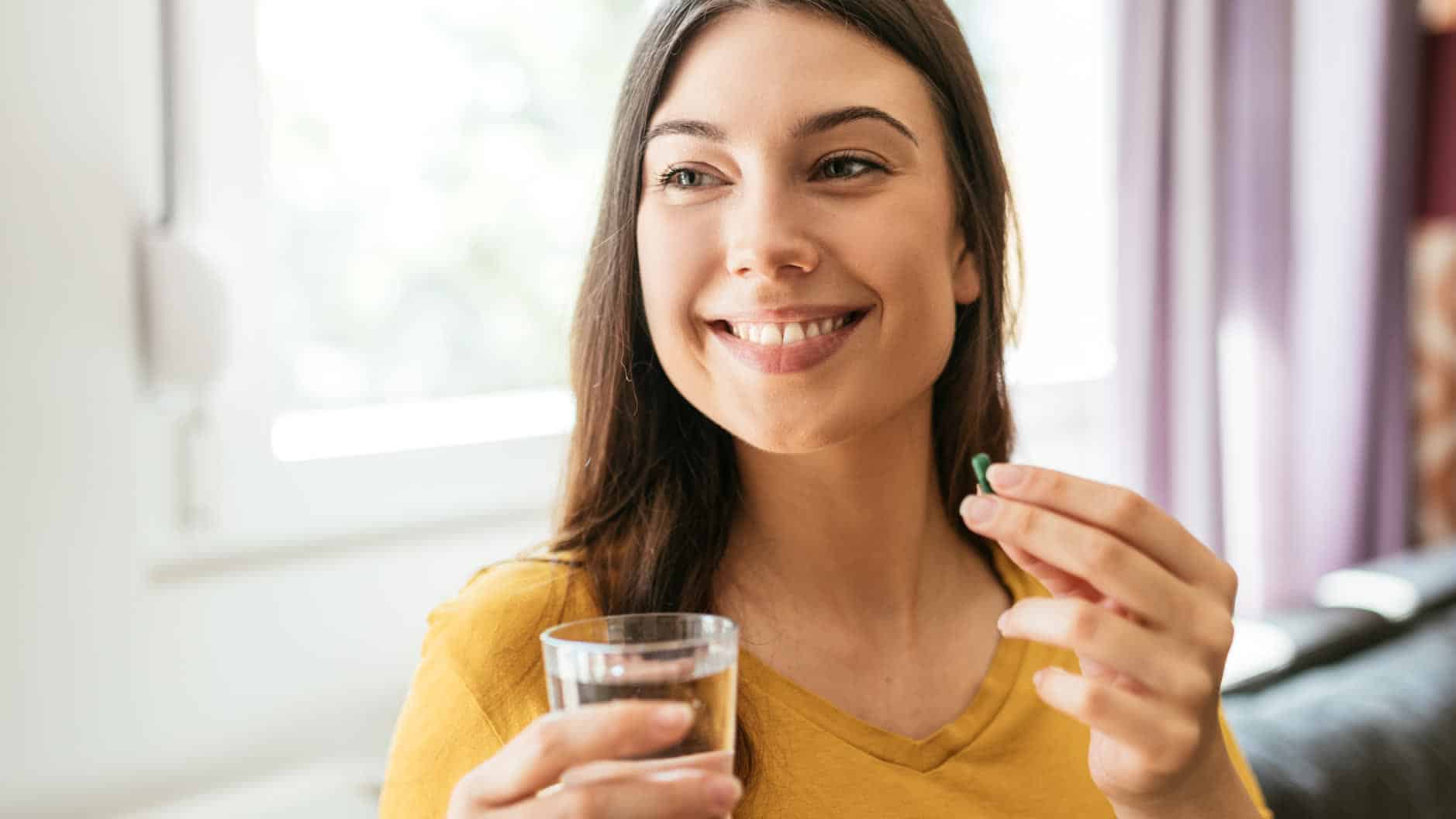 Woman taking a mineral supplement with a glass of water